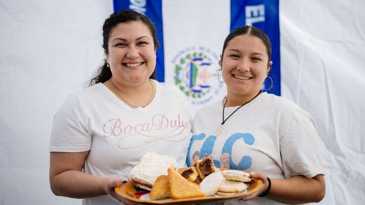 Two women smiling at the camera and holding a plate of food
